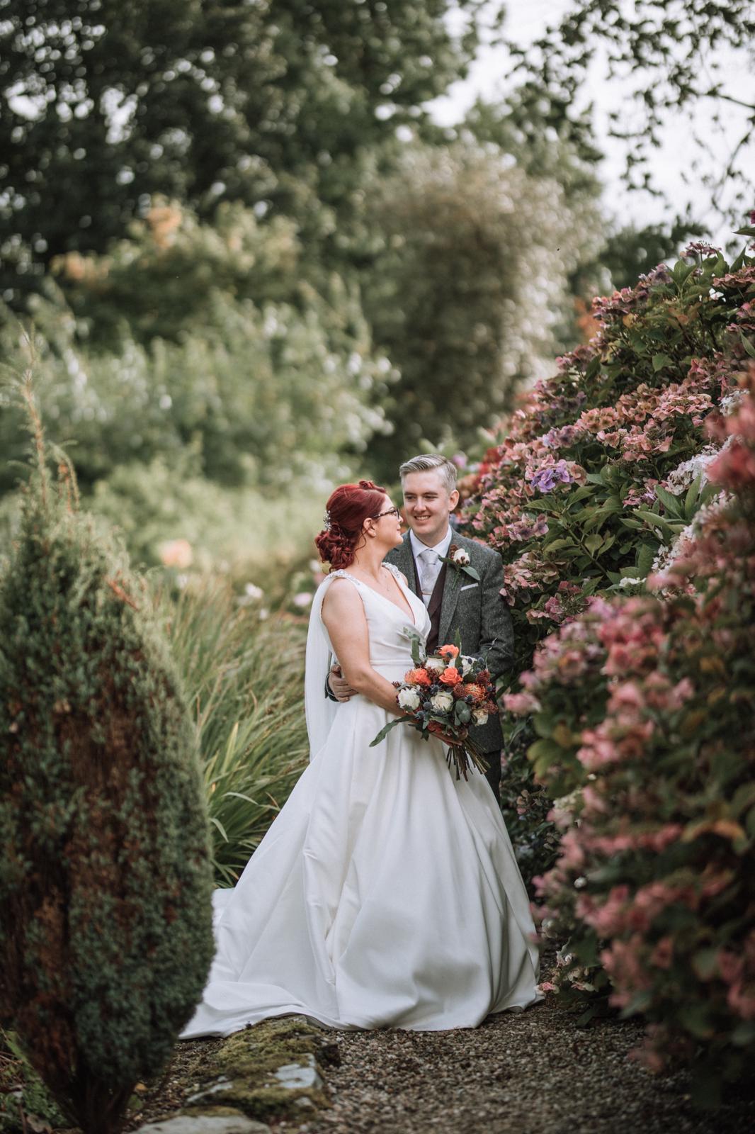 Bride and groom among the hydrangea borders in the gardens