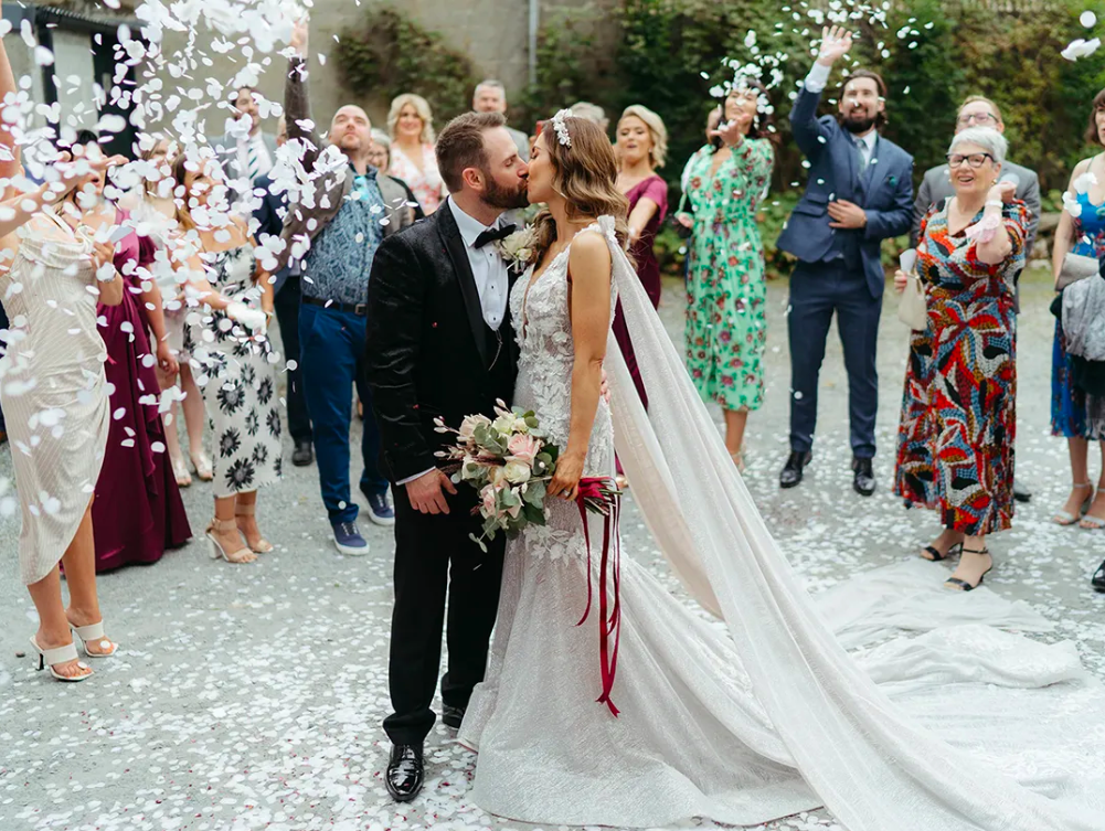 Gráinne and Mark kissing in a shower of confetti in the courtyard at Dunmore Gardens