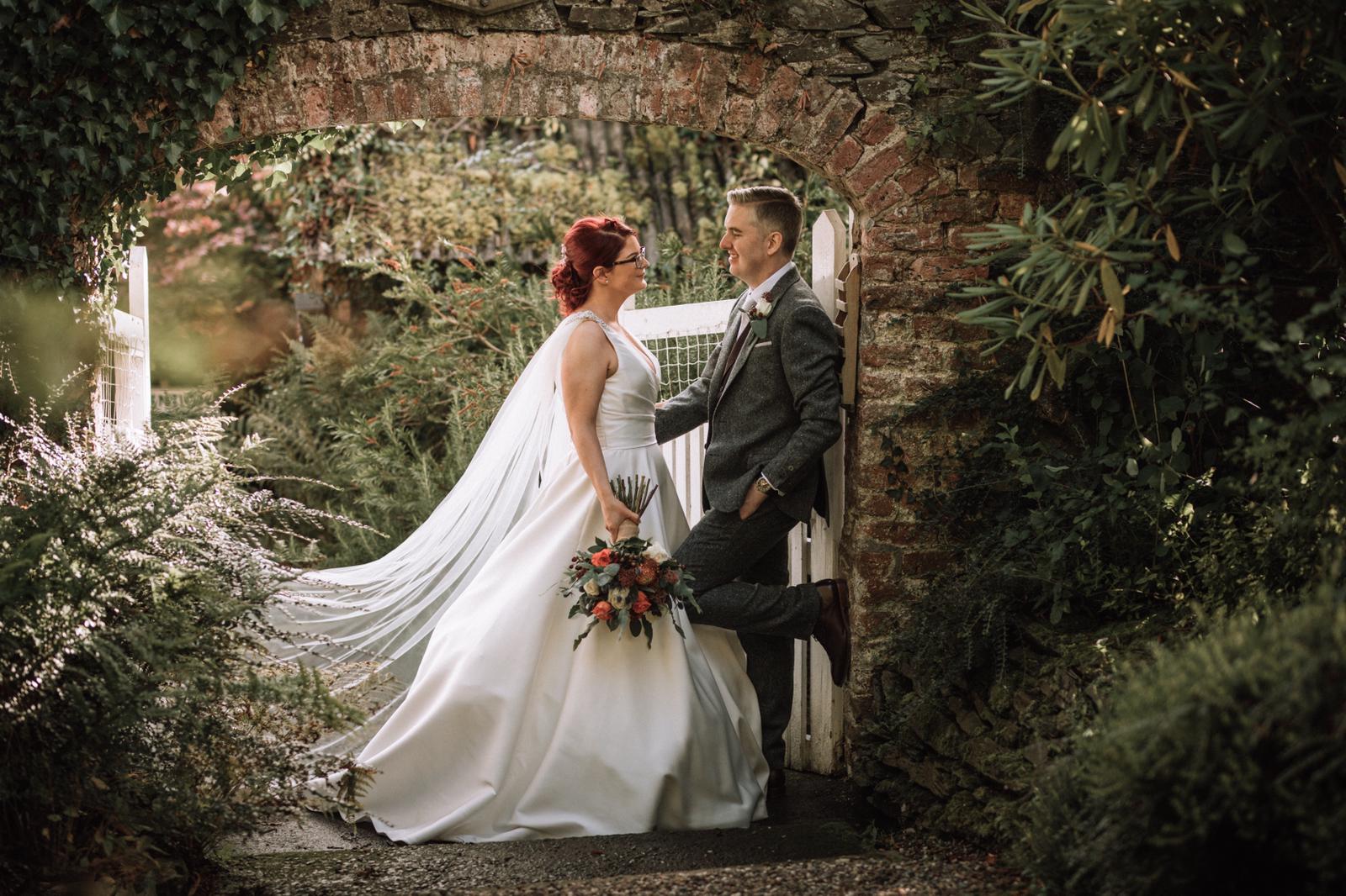 Bride and groom at the ivy-covered brick garden archway