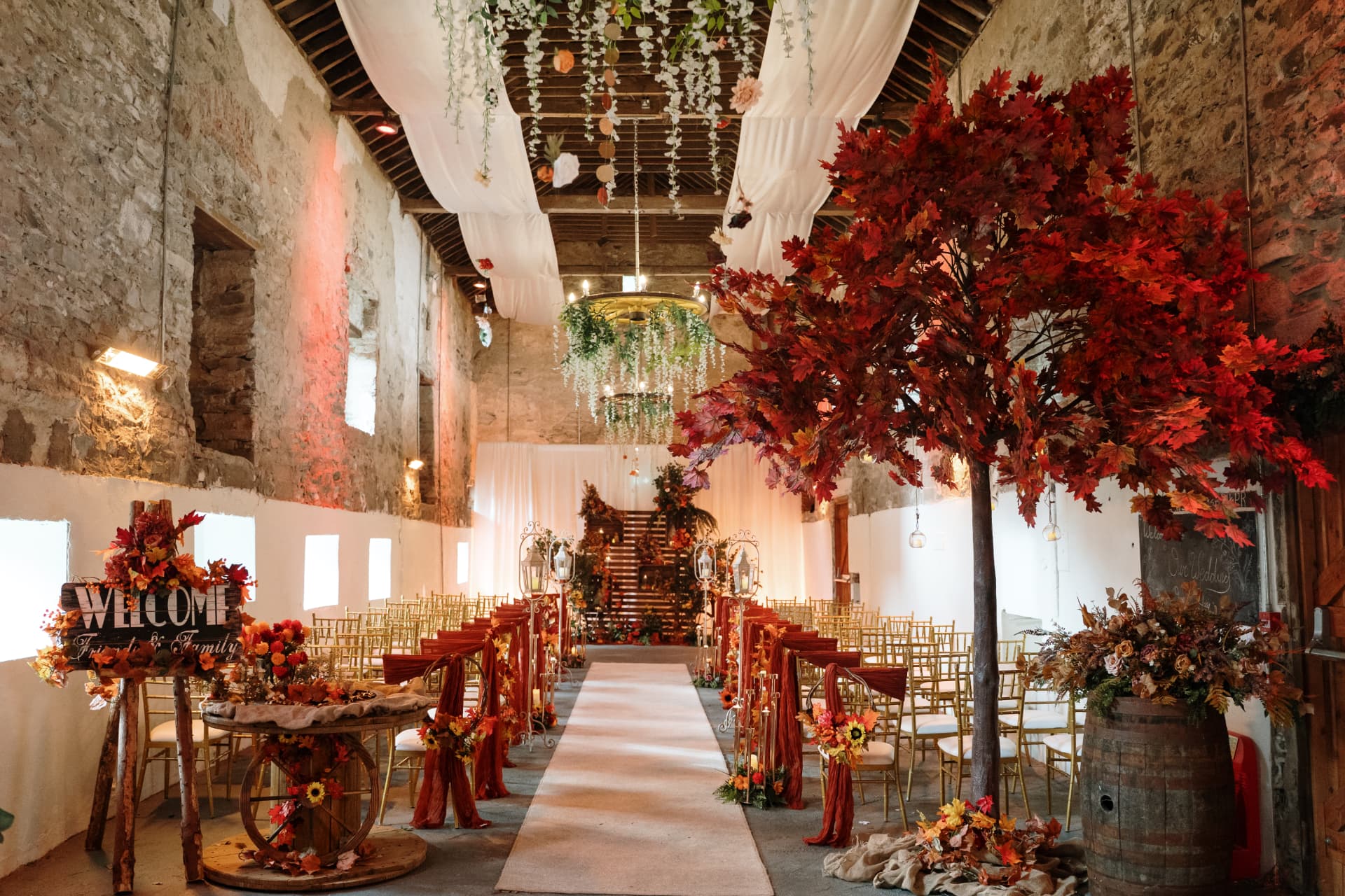 Stone barn set for an autumn ceremony with red foliage and lanterns