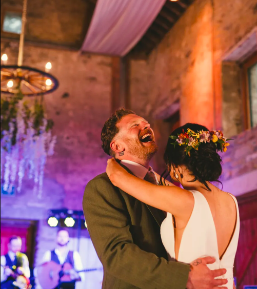 Alex and Steven laughing during their first dance in the stone barn at Dunmore Gardens
